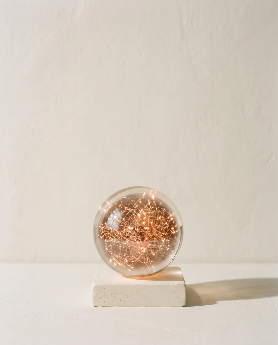 A glass sphere filled with glowing filaments on a stone base